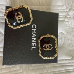 This is a pair of vintage Chanel gold-plated clip-on earrings with a black enamel inlay and CC