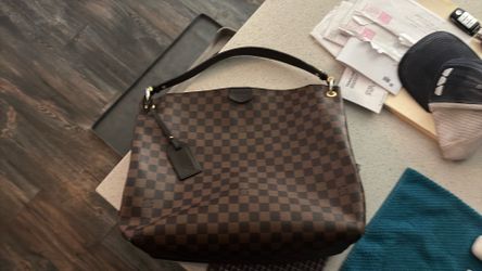This is a Louis Vuitton Graceful MM in Damier Ebene canvas with a red interior.