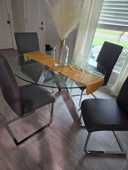 Glass dining table with 4 leather like gray chairs