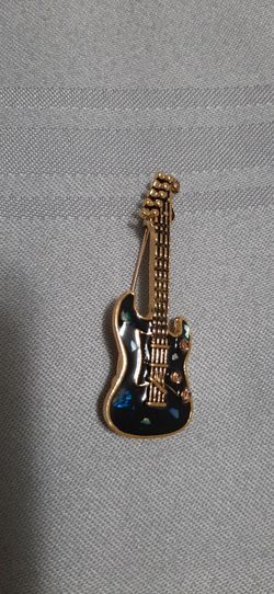 guitar-shaped brooch with intricate details.
