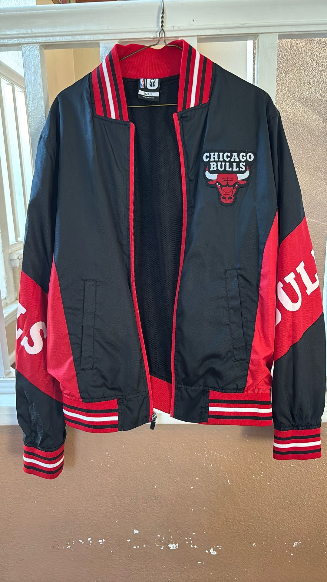 This is a black and red Chicago Bulls full-zip track jacket.