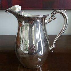 Vintage silver-plated water pitcher with scrolled handle and ice lip.