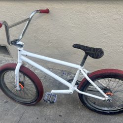 white BMX bike with red wheels and bares 