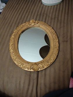 vintage or antique-style ornate oval wall mirror featuring a classic gilded frame.