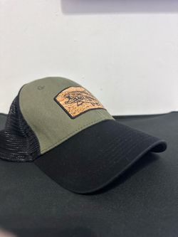 CAP OLIVE $ BLACK TRUCKER EITH CORK PATCH AND A FISH.