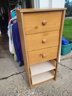 Narrow light pine chest of drawers with three upper drawers and two open storage shelves at the bottom.o e drawer front disconnected. one feont missin