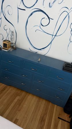 Seven drawer blue dresser with power strip and storage pocket