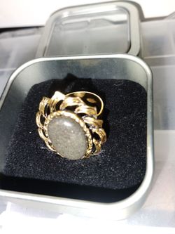 vintage gold-tone ring features an oval, textured gray stone set within an intricate, leaf-like patterned bezel adjustable $15.00
