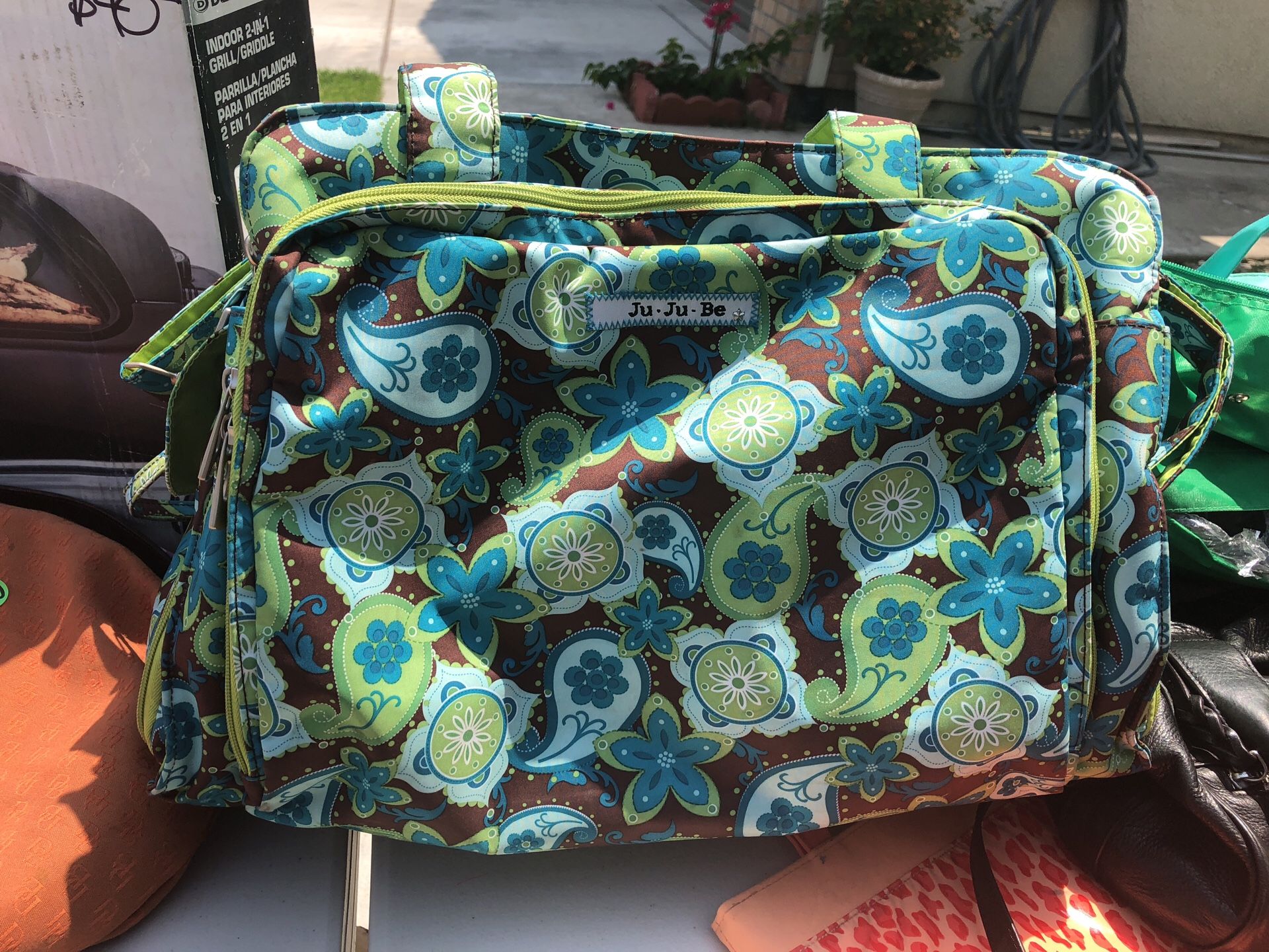 JuJuBe Be Prepared Diaper Bag with matching changing pad and pacifier pod.