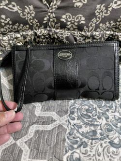 Coach New York wristlet clutch wallet featuring the classic black signature logo pattern