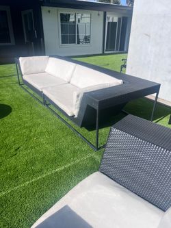 DEDON - designer brand a modern all-weather wicker (resin rattan) outdoor lounge chair with white cushions.