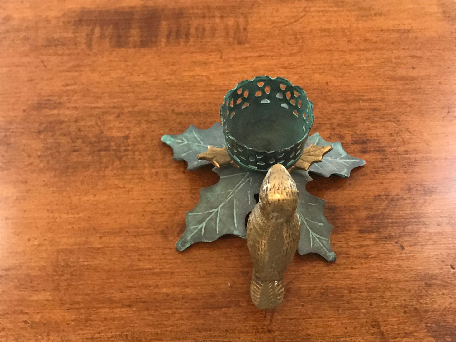 Brass bird candle holder flowers are dark green and light green leaves with small gold leaves