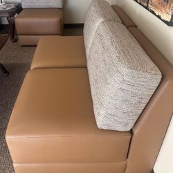 Comfortable two-seater sofas with brown leather cushions and fabric backrests.