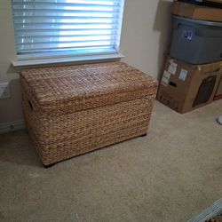 natural fiber woven storage chest with a hinged lid and wooden feet
