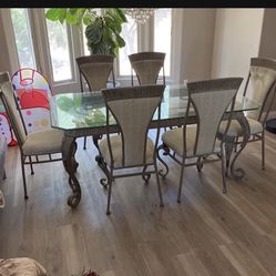 Glass table with rod iron base and 6 chairs 72” long 42” wide Vintage