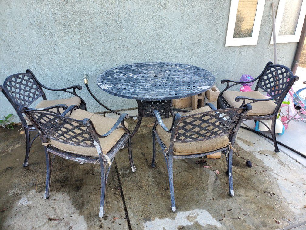 Outdoor metal table with chairs. Great restoration project, needs to be powder coated/painted. Middle hole for umbrella