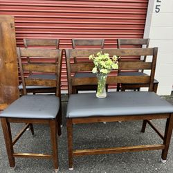 Four wooden high chairs and a bench