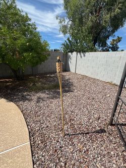 Two tiki torches and a partial bottle of citronella scented fuel