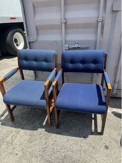 Pair of mid-century inspired 1970s blue upholstered chairs featuring tufted backrests and a dark wood frame