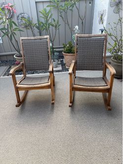 Two gray wicker and eucalyptus outdoor walking chairs and table