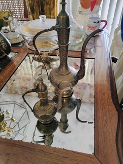 vintage brass ewers, also known as aftabas, which are traditional Indian or Middle Eastern pitchers or teapots. 