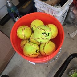 Bucket of women's fastpitch softballs.