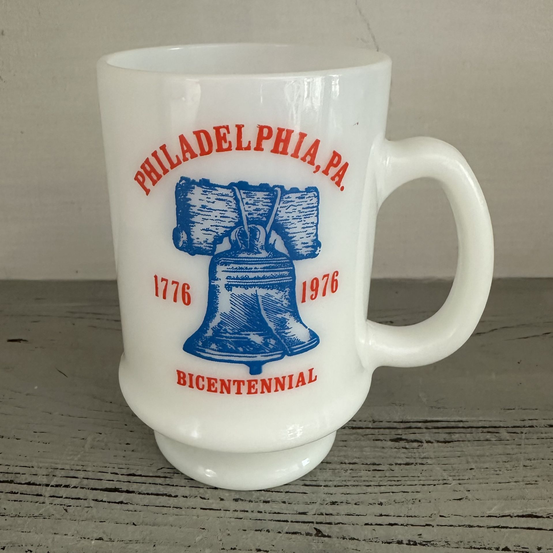 Philadelphia Bicentennial Milk Glass 1 Coffee Mug Liberty Bell 4 5/8” tall. Holds 12 oz. Graphics on one side. Red White And Blue