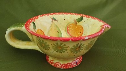 Hand-painted ceramic gravy boat with fruit and floral motifs.