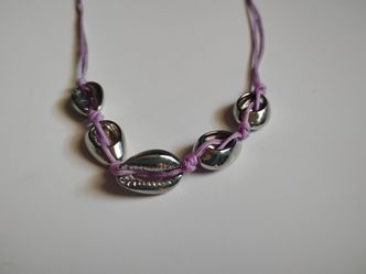 Silver tone metal seashell necklace with lavender cord