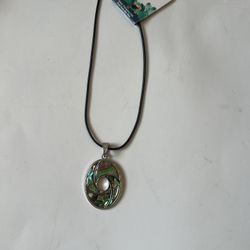 This stunning pendant necklace features a captivating swirl design in green and silver tones. Perfect for adding a touch of elegance to any outfit. Co