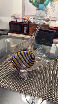 A hand-blown art glass fish sculpture with blue and yellow stripes.