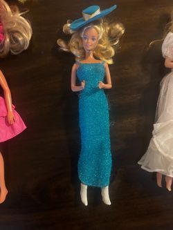 Vintage Barbie doll has a blue glittery floor-length gown with matching straps.