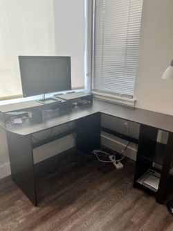Black L shaped corner desk with a monitor riser