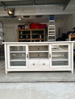 Light wood entertainment center with glass doors and drawers