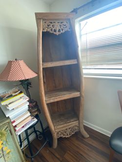 A rustic, hand- craved wooden boat bookcase