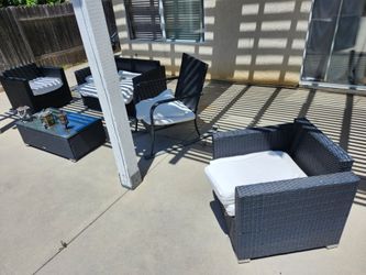 Wicker lawn furniture and glass top table with tiki lanterns +firepit bbq