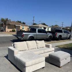 Beige Living Spaces Couch Reversible Sectional with grey storage ottoman