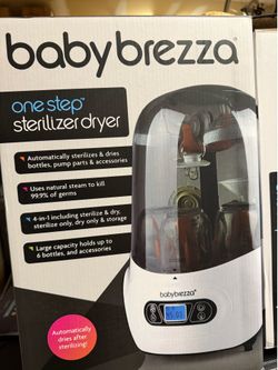 New Baby Brezza One Step Sterilizer Dryer is white with a clear top. It uses natural steam to kill germs and automatically dries bottles or pump parts