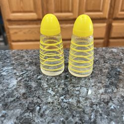 Vintage Clear Glass Yellow stripped pair of salt and pepper shakers with yellow plastic caps.  Size approximately 3 inches tall.  Preowned.  Has been 