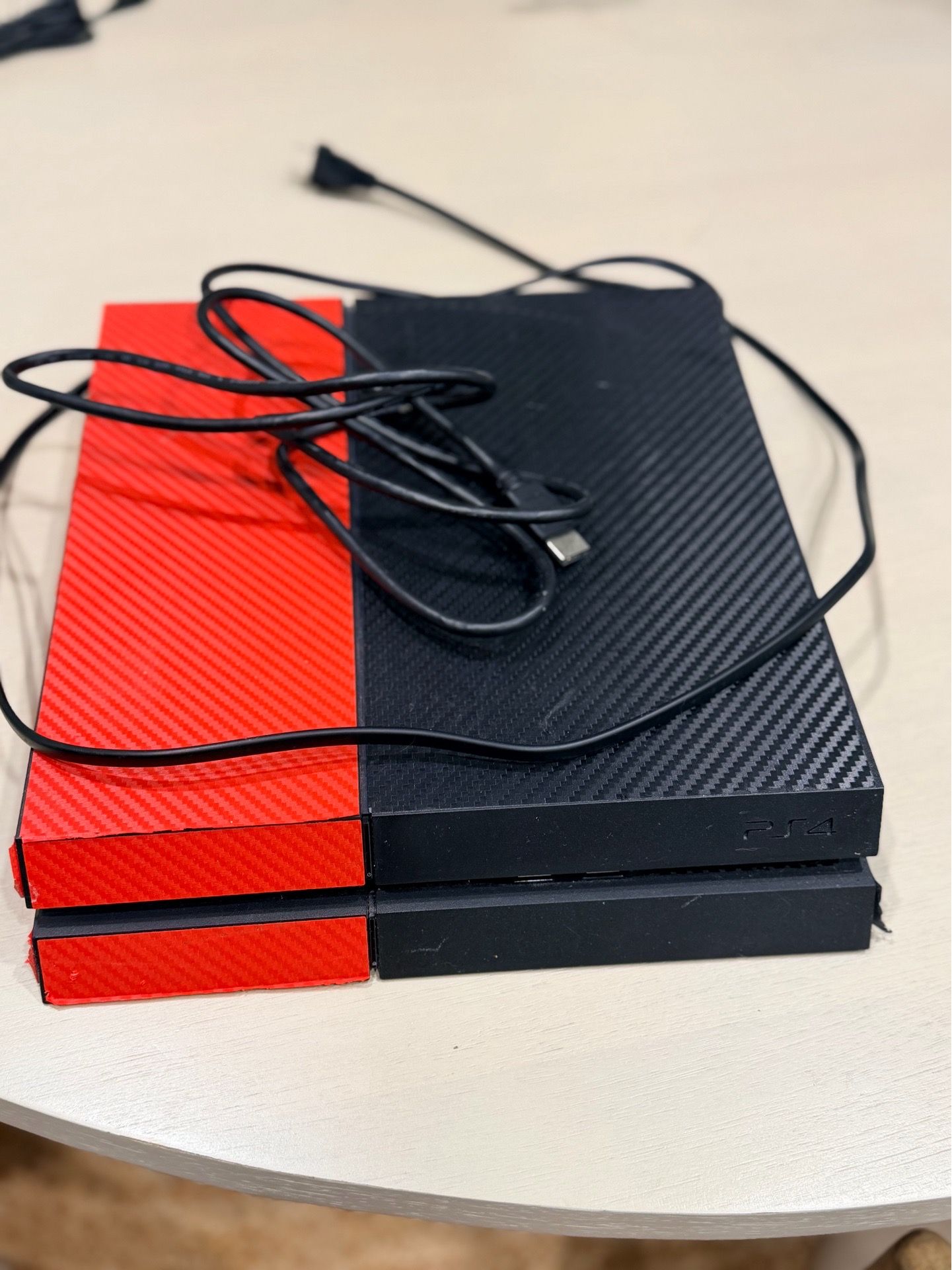 PS4 console with red and black skin with cables