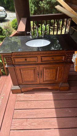 Wood Vanity with black stone top & brushed nickel faucet included. 22”x43”