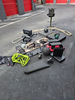 Large lot of used fitness equipment including kettlebells, medicine balls, a TRX slam ball, BOSU ball, resistance bands, gymnastic rings with straps, 