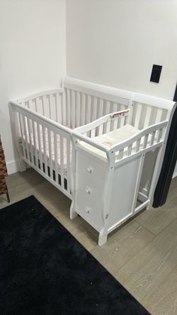 White mini crib with changing table