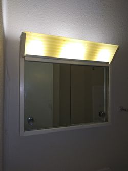 Bathroom medicine cabinet, mirrored doors and one shelf. Has a light on top for four bulbs