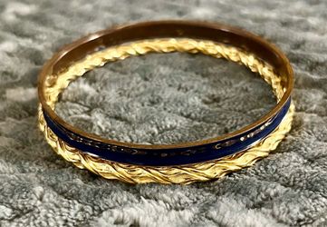 classic stacking pair of vintage bracelets: a glossy navy blue enamel bangle paired alongside a detailed, gold-toned twisted rope bangle
