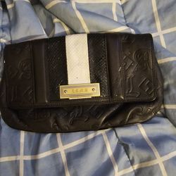This item is an L.A.M.B. brand clutch bag featuring a black leather embossed design with a white contrasting stripe and gold-tone hardware