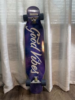 The longboard features a deck with a space-themed print and the inscription "Good Vibes."