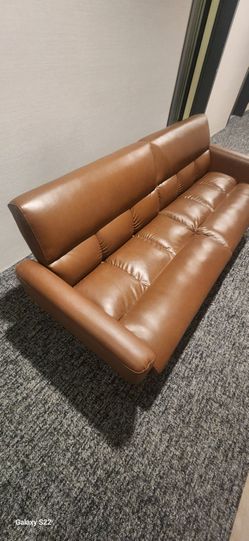 brown faux leather futon sofa bed with tufted seating.