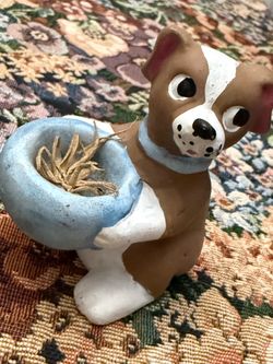 Vintage puppy holding a basket or mailbox.
