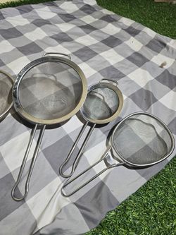 Collection of assorted stainless steel kitchen strainers and skimmers